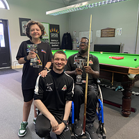A group of three young males in a snooker hall, one in a wheelchair