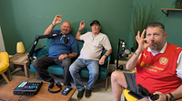 Three men in a podcast studio giving a perfect hand symbol