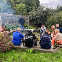 Adults sat in a circle near a BBQ