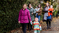 A group of young mums and their babies walking through the woods