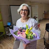 A smiling lady holding a bunch of flowers 