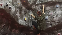 A female climbing a grey bouldering wall