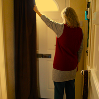 The back of a woman pulling a curtain