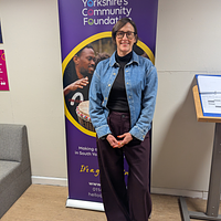 A lady stood smiling in front of a pop up banner