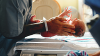 A medical professional holding a newborn baby